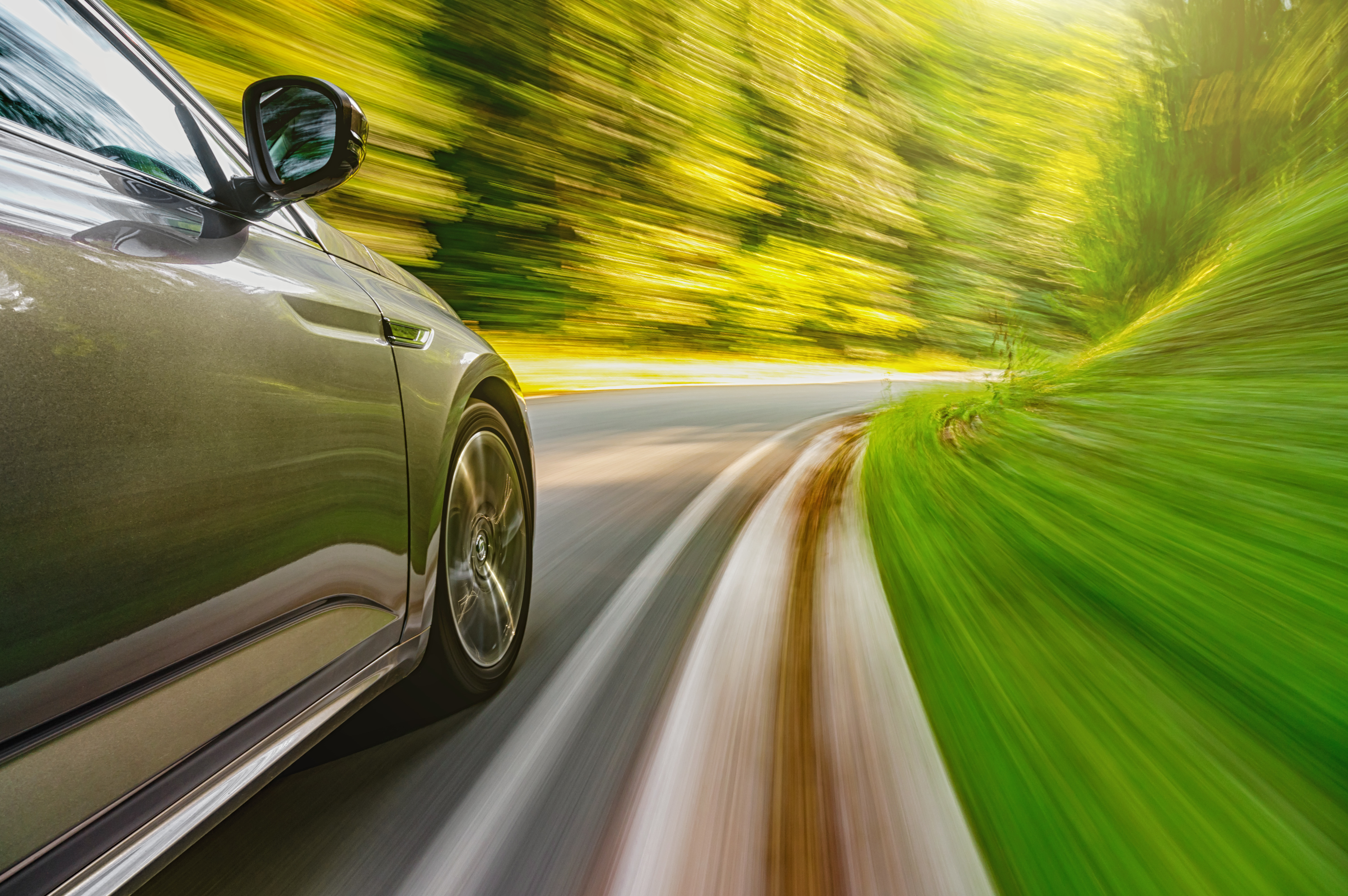 Car,Driving,Fast,On,A,Mountain,Road,Towards,Setting,Sun